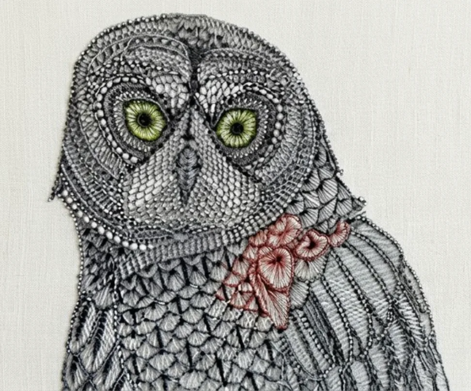 Original artwork reference: detailed ornamental black-and-white owl with vivid green eyes and reddish feather embroidery